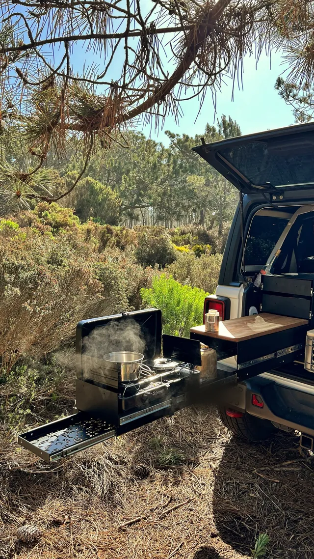 Emmer kitchen extended from a car under pine trees, a pot steaming on the stove