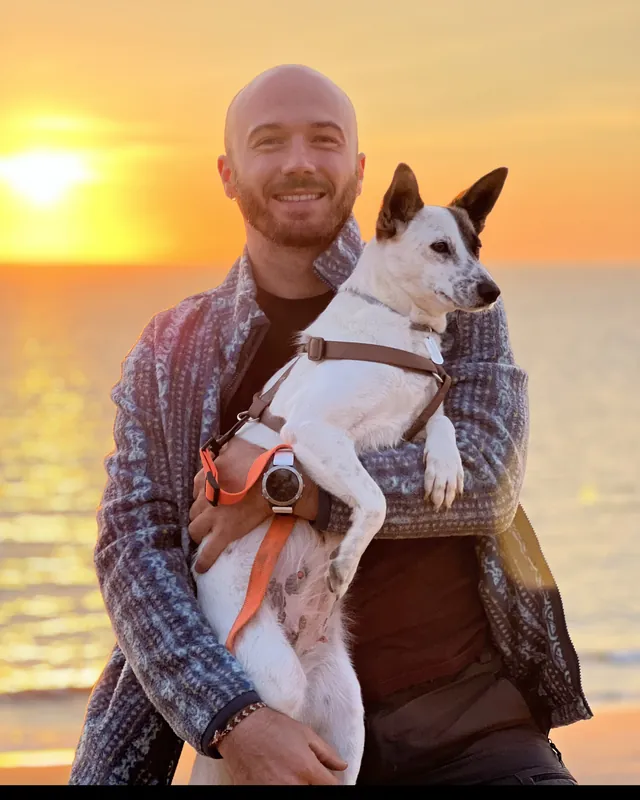 Alex Solovei, founder of Emmer, with his dog at sunset by the ocean