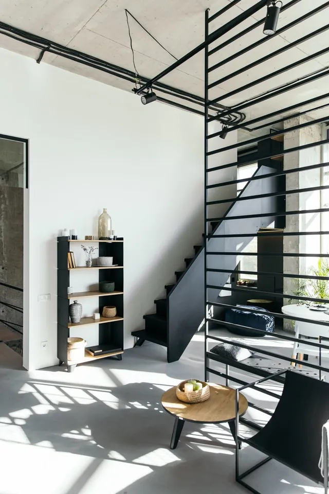 Loft interior with black steel shelving, a steel staircase and a round wooden table