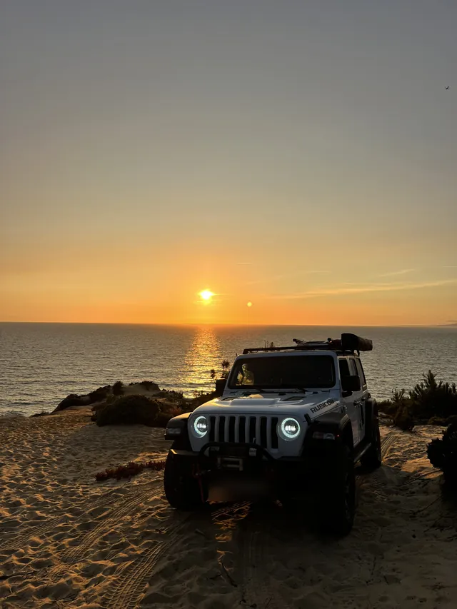 Vehicle parked on the beach at sunset